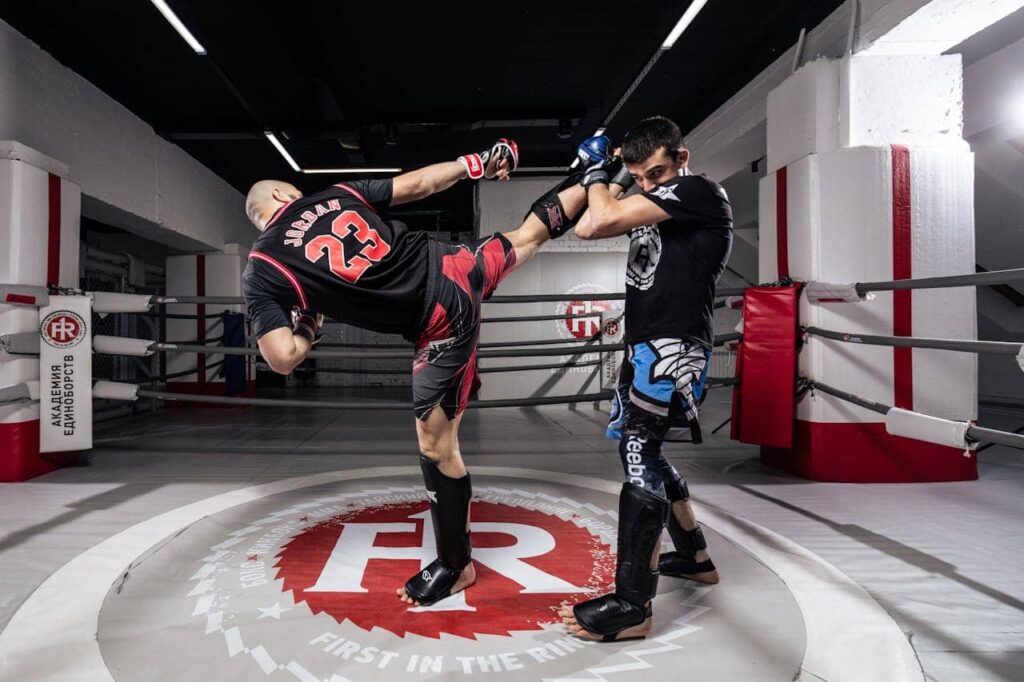 Choisir protege tibia boxe : un boxeur donne un coup de pied à son adversaire